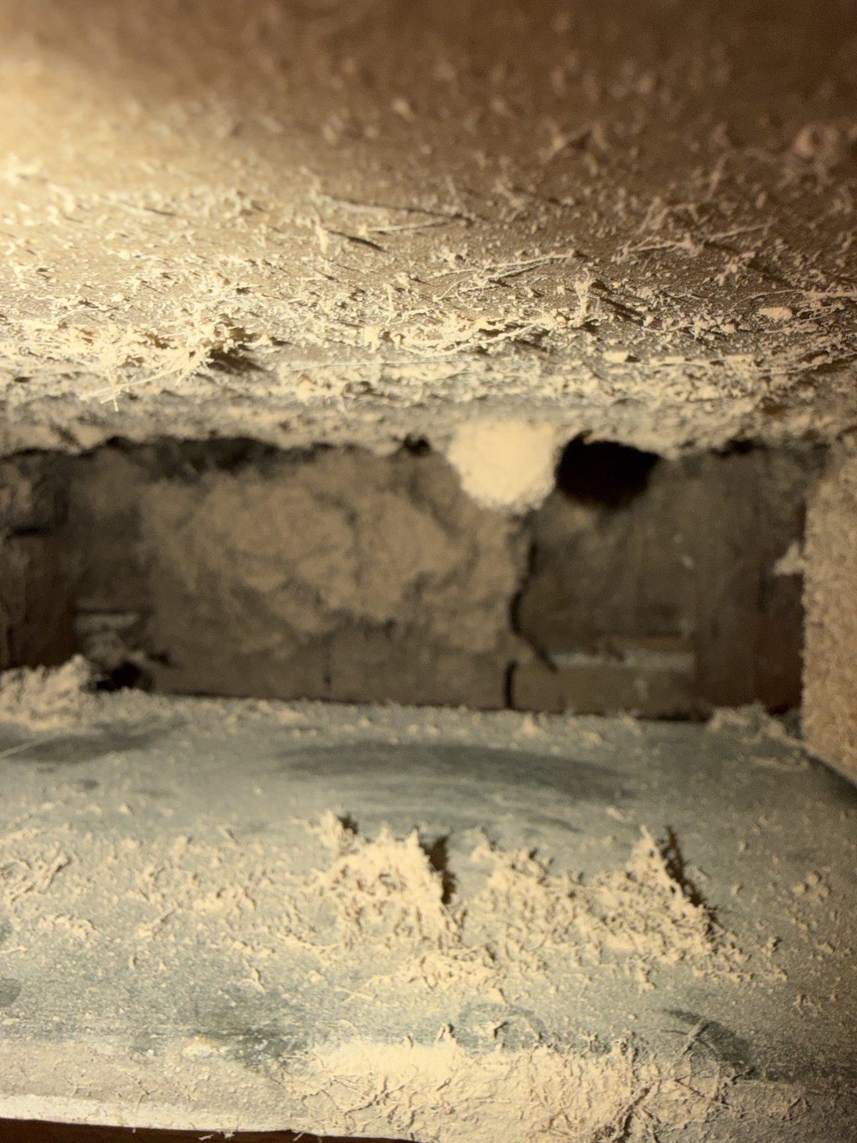 Dust piled over the inside of a wood lined duct, before cleaning